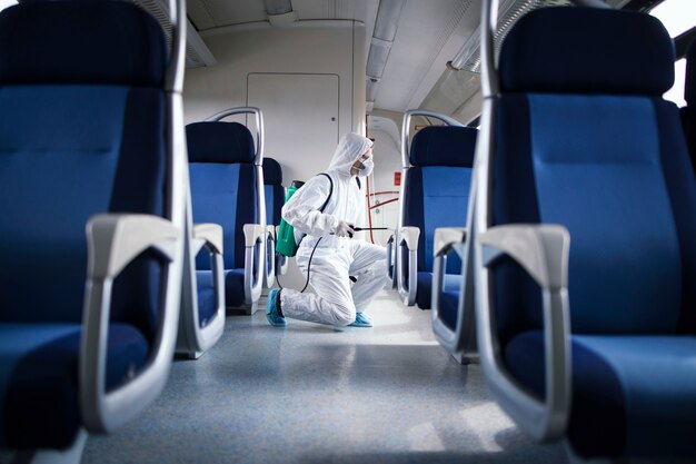 Homme en costume de protection blanc désinfectant et désinfectant l'intérieur de la rame de métro pour arrêter la propagation du virus corona très contagieux