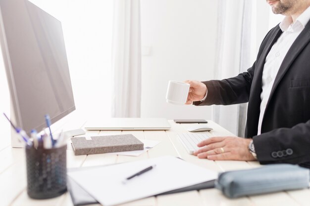 Homme de côté ayant une tasse de café à son bureau