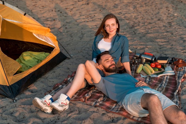 Photo gratuite homme couché sur les genoux de sa petite amie près de la tente