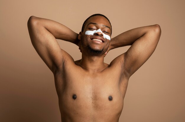 Homme de coup moyen avec de la crème pour le visage