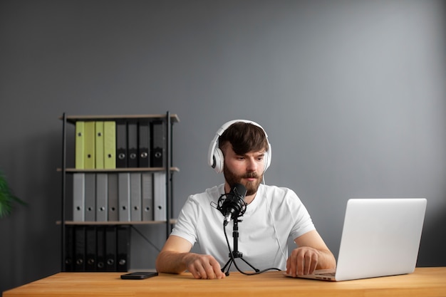 Photo gratuite homme à coup moyen enregistrant un podcast avec un casque