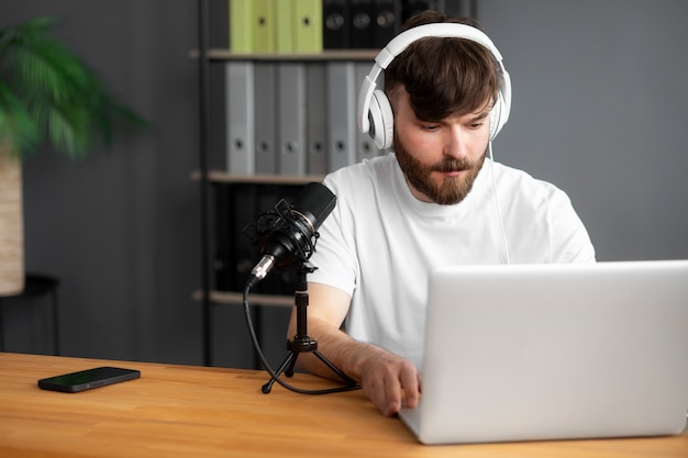 Homme à coup moyen enregistrant un podcast avec un ordinateur portable