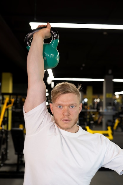 Photo gratuite homme à coup moyen s'entraînant avec un kettlebell bleu