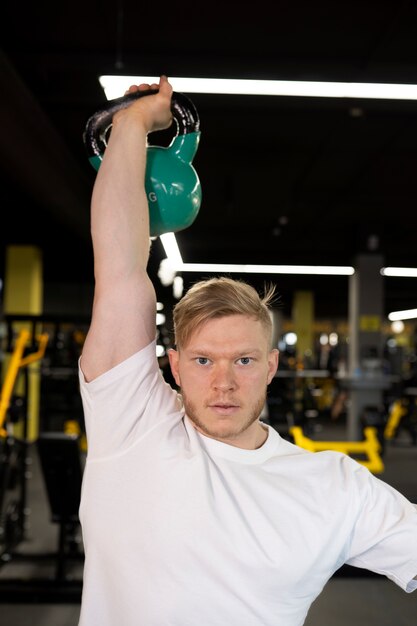 Homme à coup moyen s'entraînant avec un kettlebell bleu