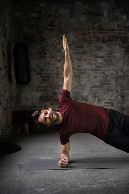 Homme à coup moyen s'entraînant avec un tapis de yoga