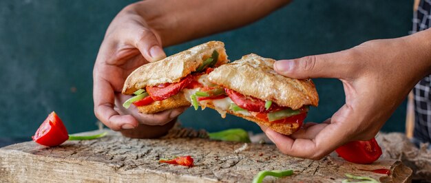 Homme coupant avec les mains sucuk ekmek, sandwich au saucisson au poulet et aliments mélangés