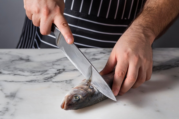 Homme coupant un poisson de basse pour la cuisine