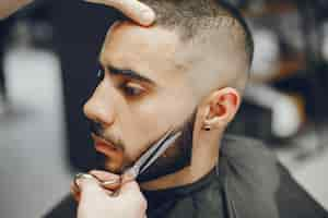 Photo gratuite l'homme coupe sa barbe dans le salon de coiffure.