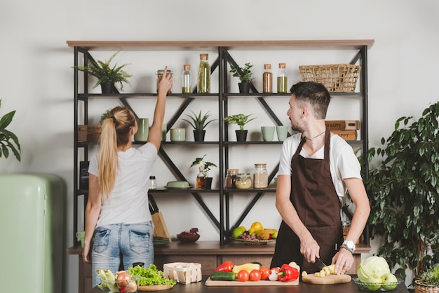 Homme, couper, légumes, regarder, femme, prendre, bouteille, depuis, étagère