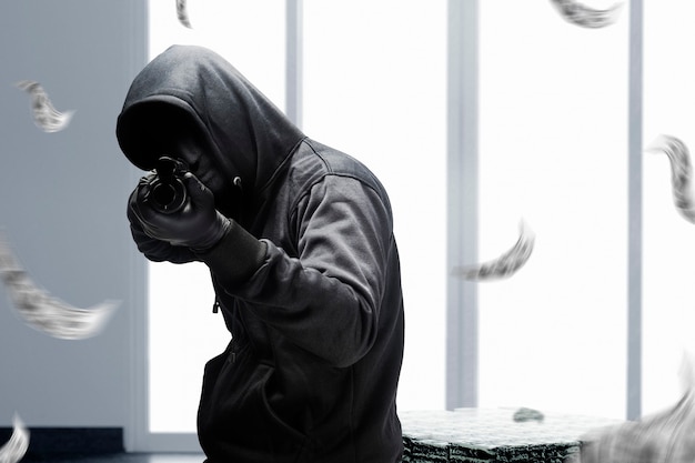 Photo gratuite homme criminel en masque caché pointant le fusil de chasse pendant le vol de l'argent à la banque