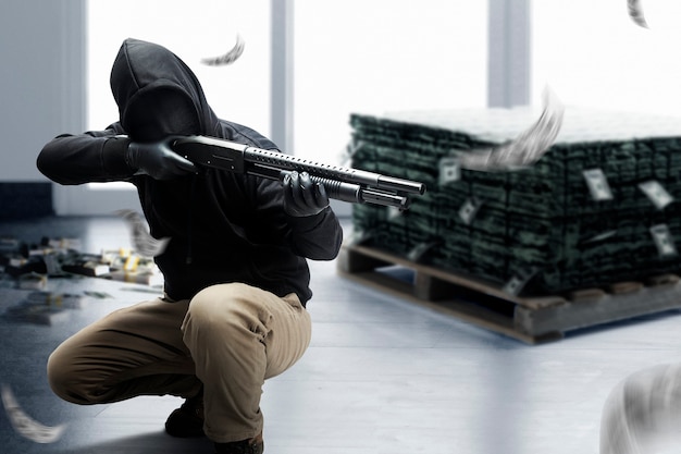 Homme criminel en masque caché pointant le fusil de chasse pendant le vol de l'argent à la banque