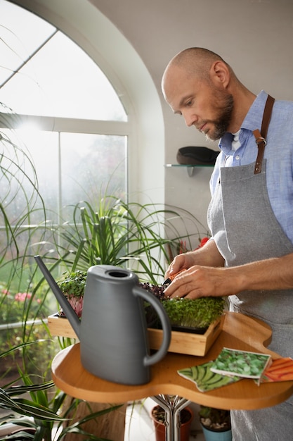 Photo gratuite homme cultivant et cultivant des plantes dans un jardin intérieur