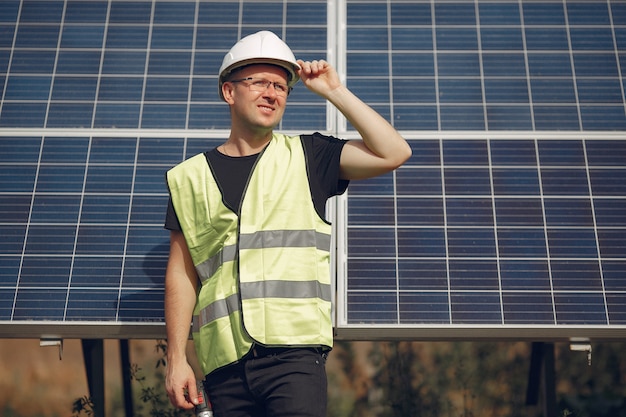 Homme dans un casque blanc près d'un panneau solaire