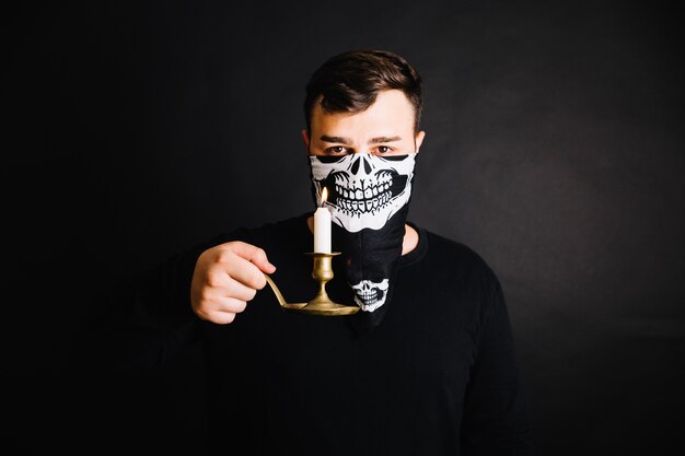 Homme dans le masque de squelette posant avec des bougies