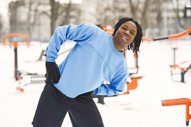 Homme dans un parc d'hiver. Un homme africain s'entraîne à l'extérieur.