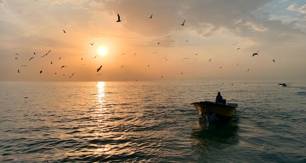 Homme dans une petite barque au milieu de la belle mer avec le soleil qui brille