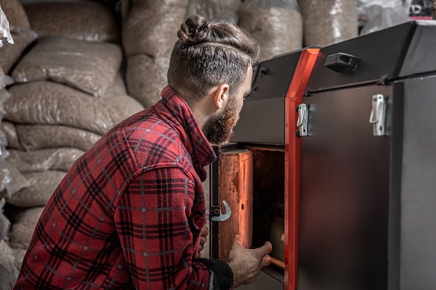 Un Homme Dans Une Pièce Avec Une Chaudière à Combustible Solide, Travaillant Au Biocarburant, Chauffage économique.