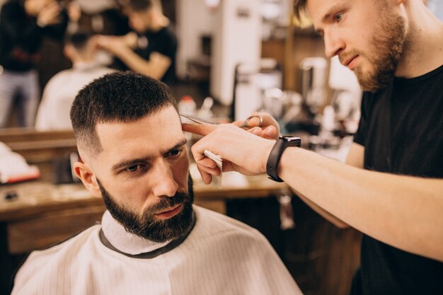 Homme dans un salon de coiffure pour coiffeur et coupe de barbe