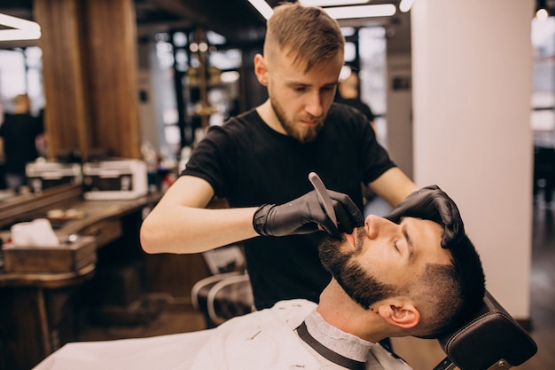 Homme dans un salon de coiffure pour coiffeur et coupe de barbe