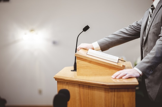 Photo gratuite homme dans une tenue formelle prêchant la sainte bible de la tribune à l'autel de l'église