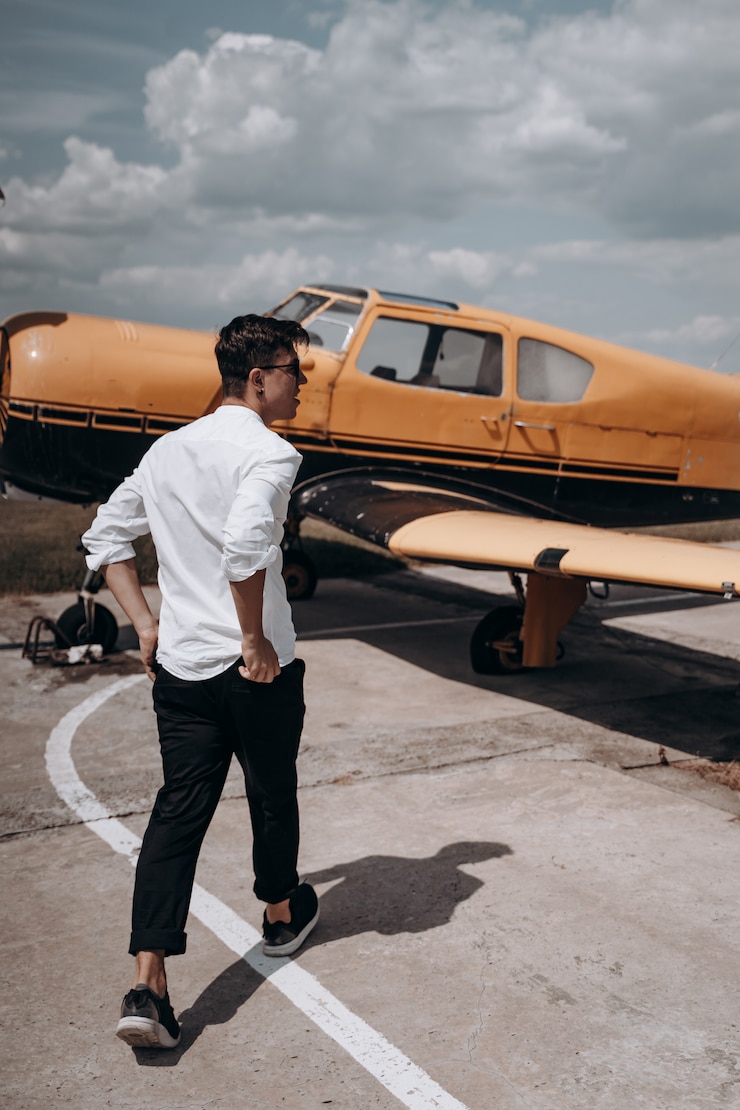 Photo gratuit un homme debout sur l'arrière-plan d'un petit avion monomoteur.