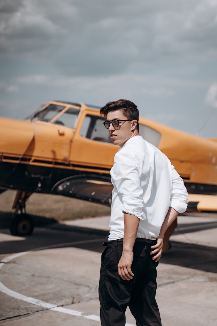 Photo gratuit un homme debout sur l'arrière-plan d'un petit avion monomoteur.