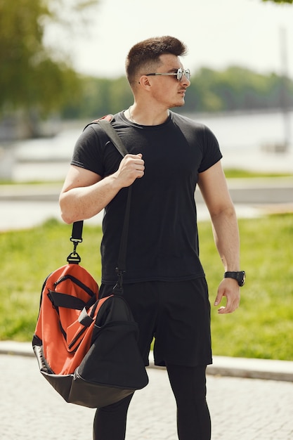 Homme Debout Au Bord De L'eau. Guy Dans Un Vêtement De Sport. Mâle Dans Un Parc D'été Avec Sac à Dos