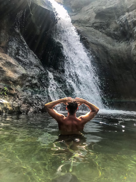 Photo gratuite homme debout au lac avec cascade