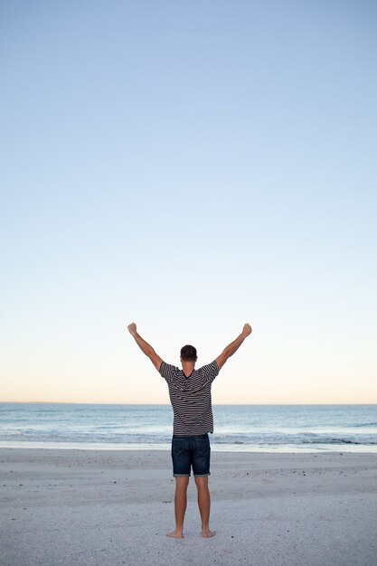 Homme debout avec les bras sur la plage