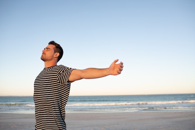 Homme debout avec les bras tendus sur la plage