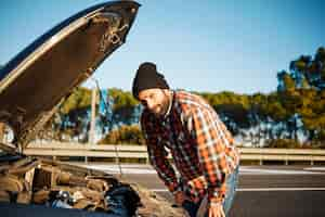 Photo gratuite homme debout à côté de sa voiture cassée