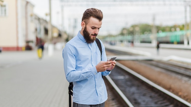 Homme debout à la gare à l&#39;aide de téléphone portable