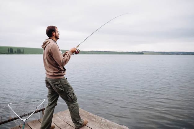 Homme debout sur la jetée de pêche dans le lac