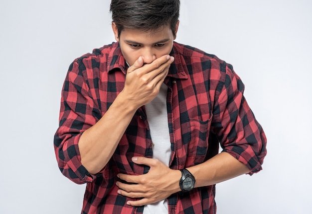 Photo gratuite un homme debout avec un mal de ventre mettez vos mains sur votre ventre et couvrez-vous la bouche.