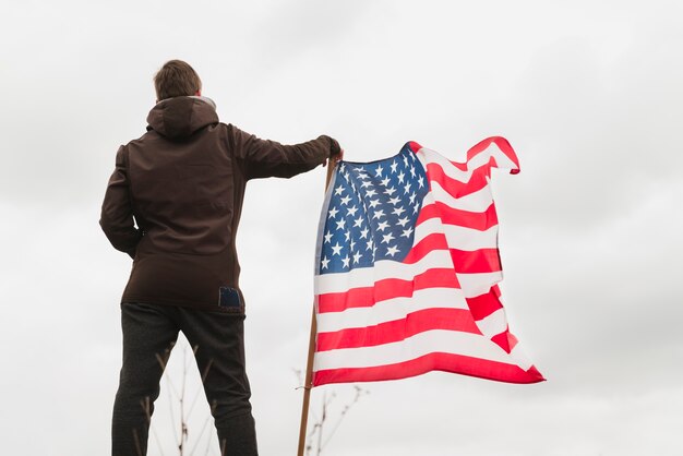 Homme debout près du drapeau américain