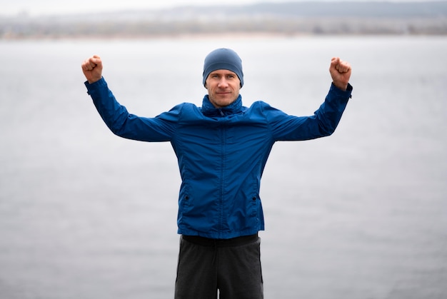 Homme debout près du lac avec les bras en l'air