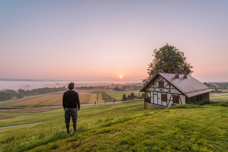 Photo gratuit un homme debout près de la maison et de l'arbre pendant la journée