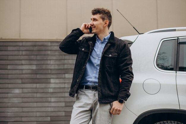 Homme debout près de sa voiture et parler au téléphone