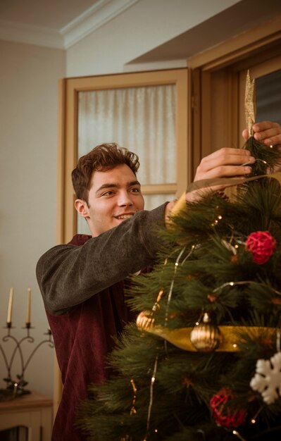 Homme décorer un arbre de Noël avec étoile