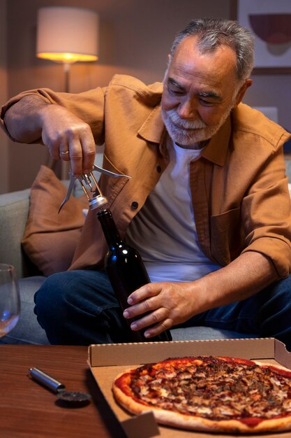 Homme dégustant une pizza et du vin tout en étant seul à la maison