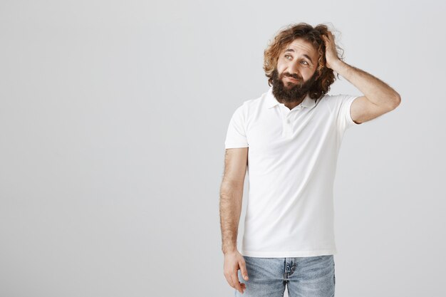 Homme désemparé hésitant sur le choix, se gratte la tête et semble troublé à gauche