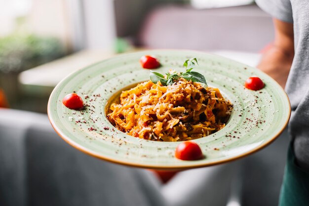 Homme détient des pâtes fettuccine poulet champignon parmesan tomate menthe sumakh vue latérale