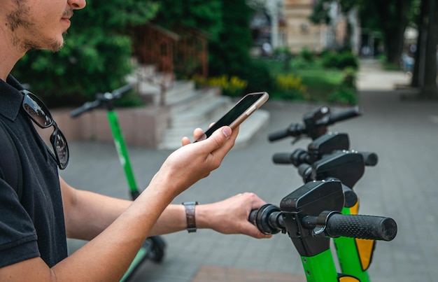 Photo gratuite un homme déverrouille un escooter avec son téléphone portable