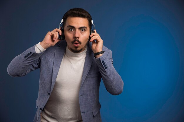 Homme dj en costume gris écoutant des écouteurs et se fait surprendre.