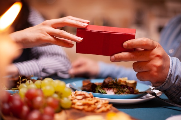 Homme donnant une boîte-cadeau à sa femme et prenant un dîner romantique ensemble