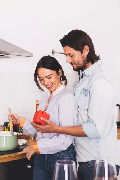 Homme donnant une petite boîte cadeau à une femme dans la cuisine