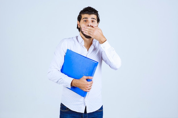 L'homme avec le dossier bleu a l'air confus ou terrifié