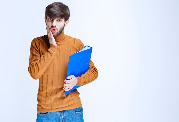 L'homme avec un dossier bleu a l'air confus et terrifié.