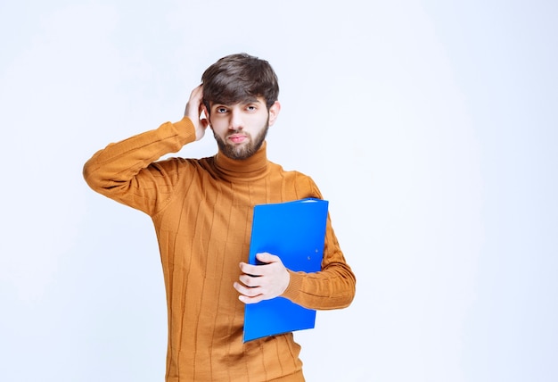 L'homme avec un dossier bleu a l'air confus et terrifié.