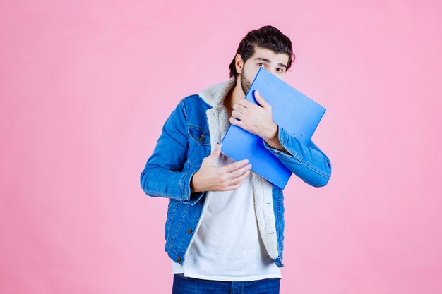 L'homme avec un dossier bleu a l'air terrifié et fatigué